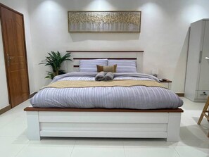 Une chambre à coucher moderne avec un grand lit, une table de chevet, une lampe et une armoire.