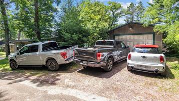 Tres vehicles de l'estil pickup estacionats a la entrada d'una casa, amb un garatge al fons.