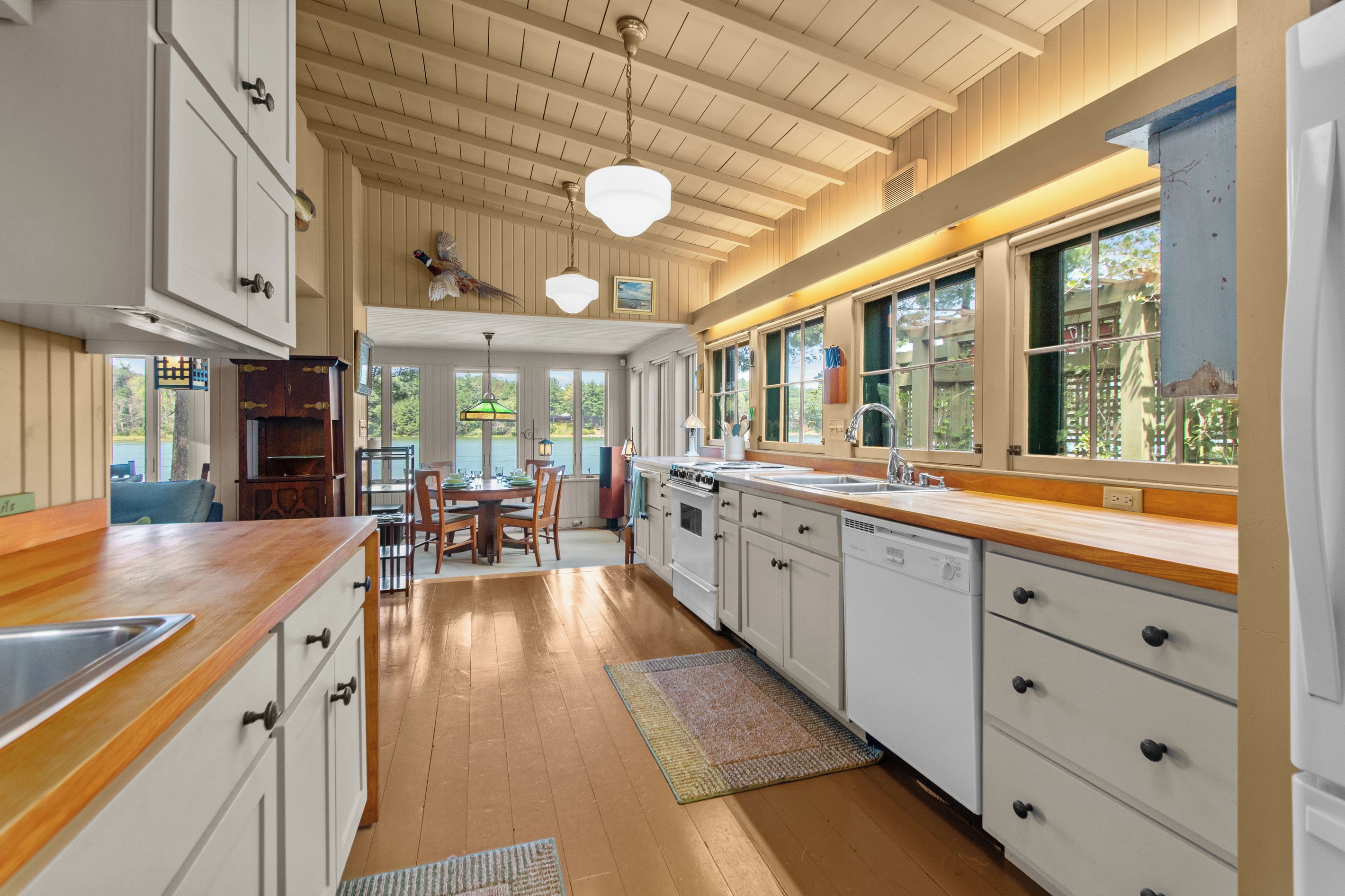 A kitchen with wooden cabinets, a dining table, and large windows.