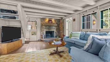 A living room with a stone fireplace, a television, and a sofa.
