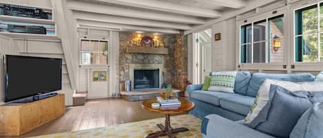 A living room with a stone fireplace, a television, and a sofa.
