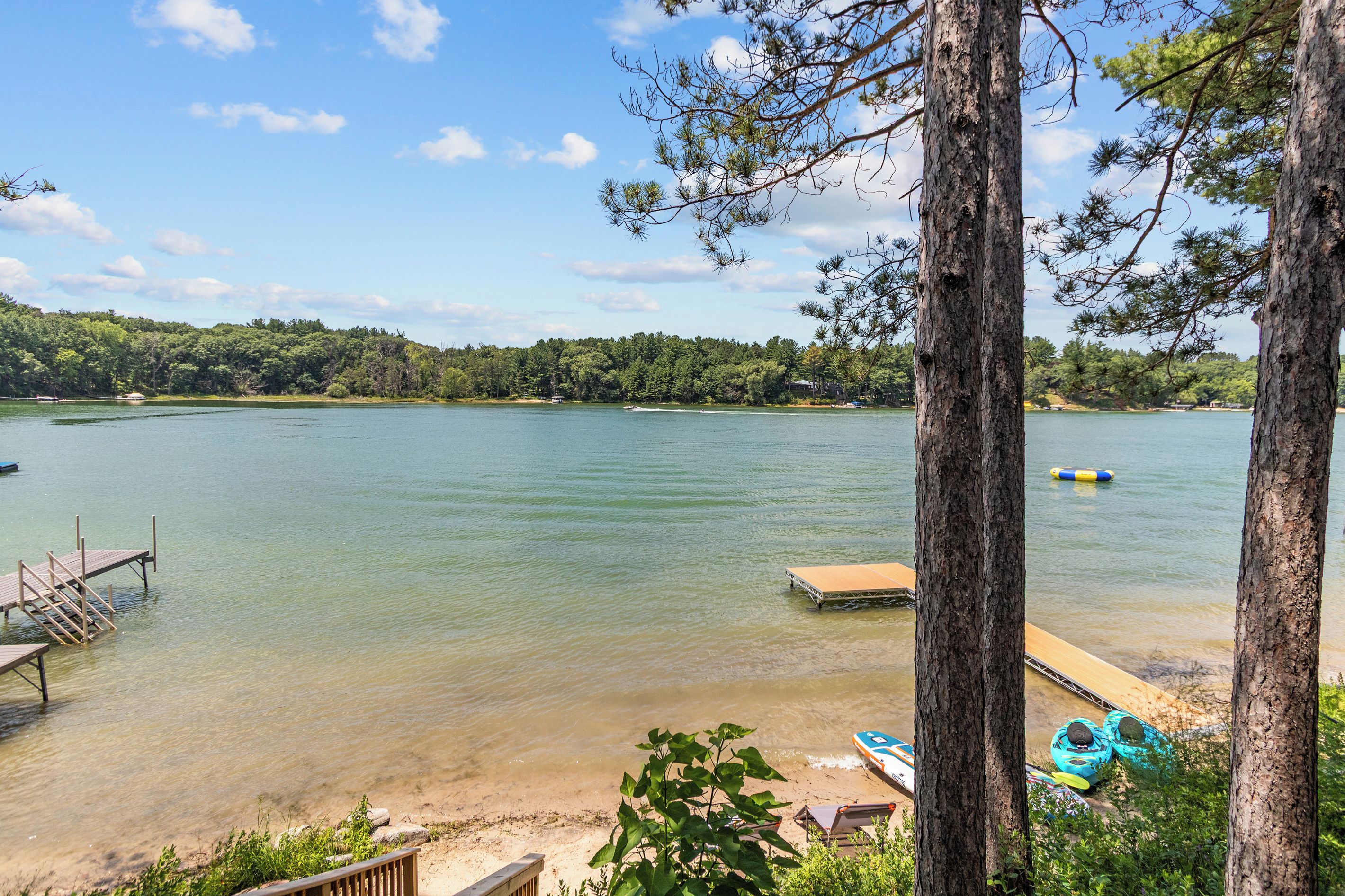 A lake with clear water, a dock, and kayaks.