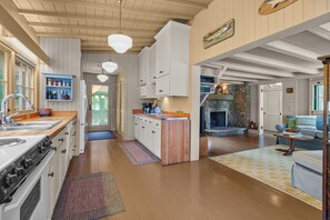 Une cuisine spacieuse avec des meubles en bois, un îlot central et une cheminée en pierre.