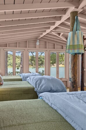 A room with two beds, a large window, and a view of a lake.