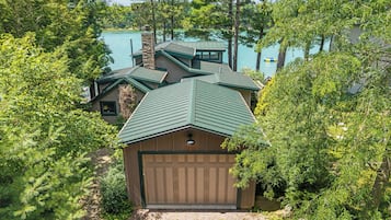 A house with a green roof, a garage, and a view of a lake.