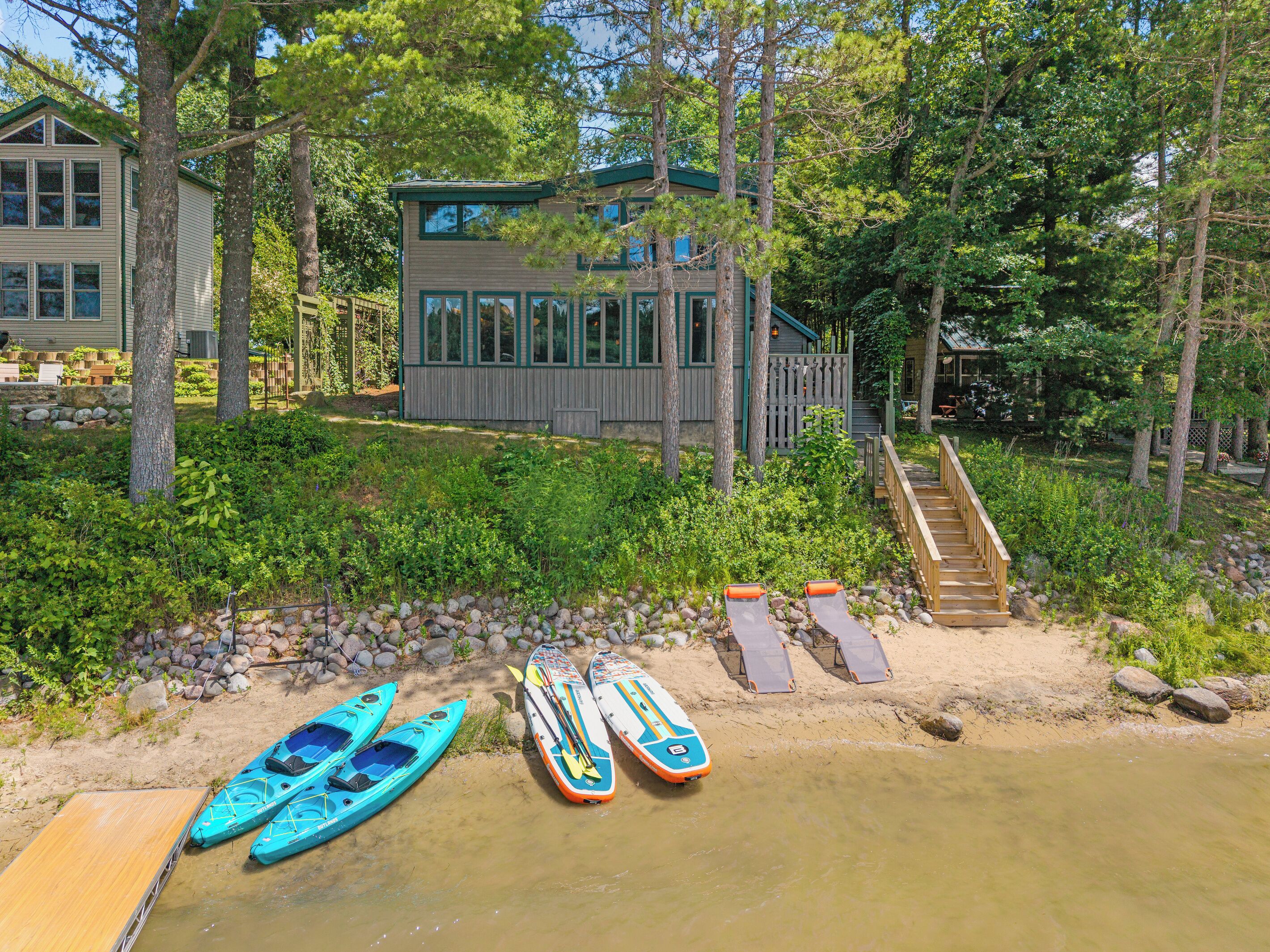 A lakeside cabin with kayaks and paddleboards by the water.