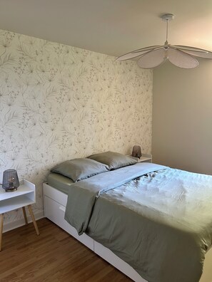 Ein Schlafzimmer mit Bett, Nachttischen, einer Lampe und einem Deckenventilator.