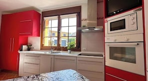 Una cocina con armarios rojos, una ventana con vistas y un microondas.