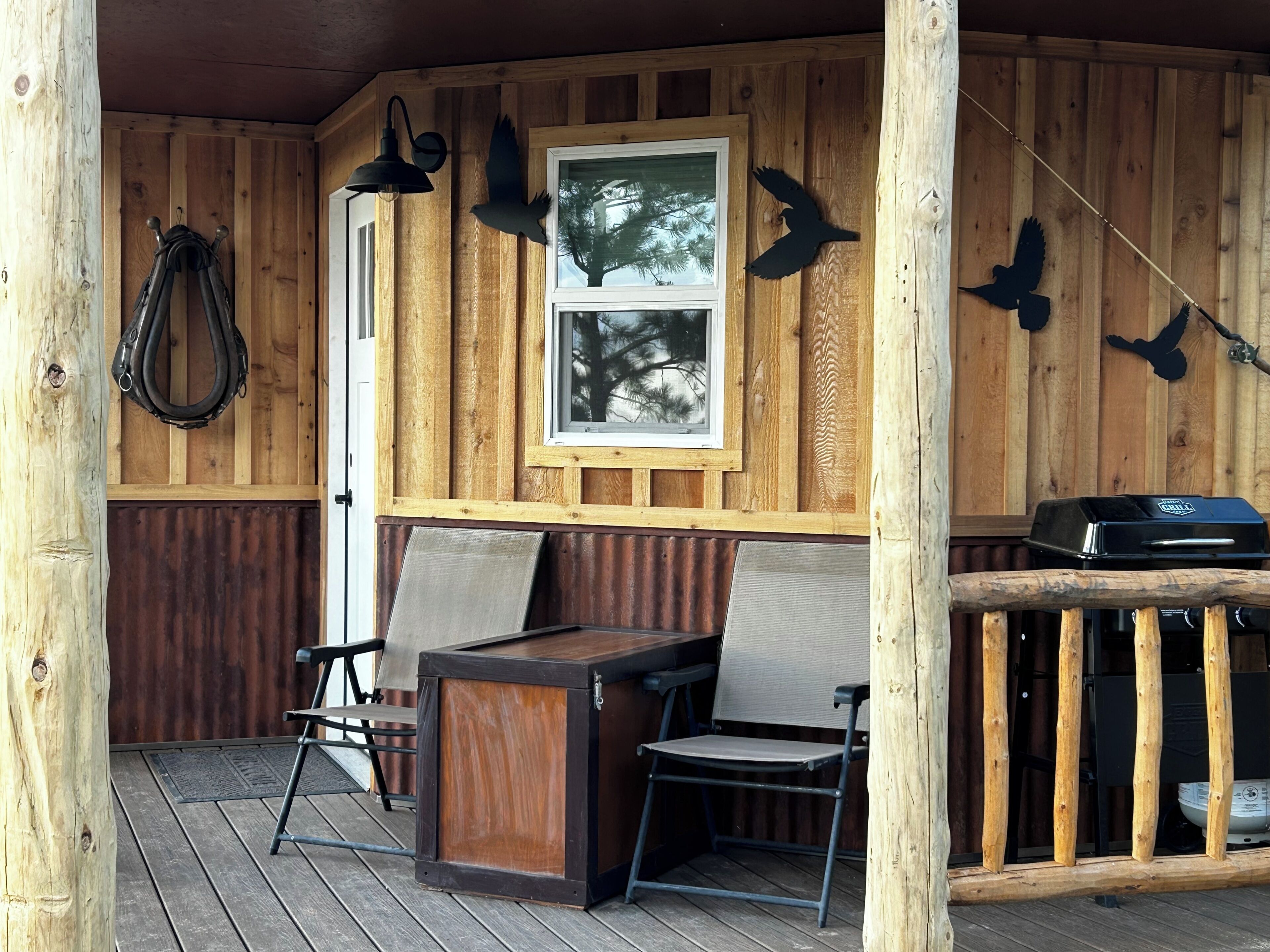 Une terrasse en bois avec un barbecue, des chaises et une table.
