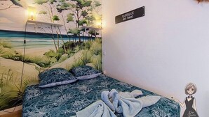 Un dormitorio con un mural de playa, una cama con ropa de cama estampada y un letrero en la pared.