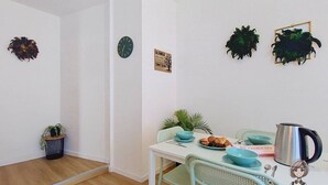 Un área de comedor con una mesa dispuesta para dos, un reloj y decoración en la pared.