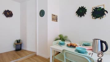 A dining area with a table set for two, a clock, and decorative wall art.