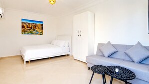 Une pièce comprenant un lit, un canapé, une petite table ronde et un tableau accroché au mur.