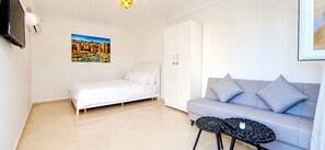 Ein Zimmer mit einem Bett, einer Couch, einem kleinen runden Tisch und einem Bild an der Wand.