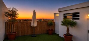 A rooftop terrace with artificial grass, potted plants, and a view of a cityscape at sunset. - Penthouse  Appartment close to Agadir Beach (Agadir)