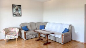 Ein Wohnzimmer mit grauem Sofa, einem floralen Sessel und einem Holztisch.