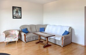 Ein Wohnzimmer mit grauem Sofa, einem floralen Sessel und einem Holztisch.