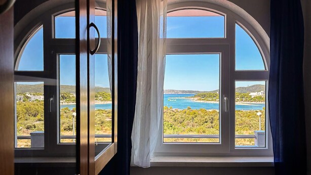 Ein Zimmer mit einem großen Rundbogenfenster mit Blick auf eine Küstenlandschaft.