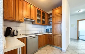 Cocina con armarios de madera, microondas, lavavajillas y cafetera.