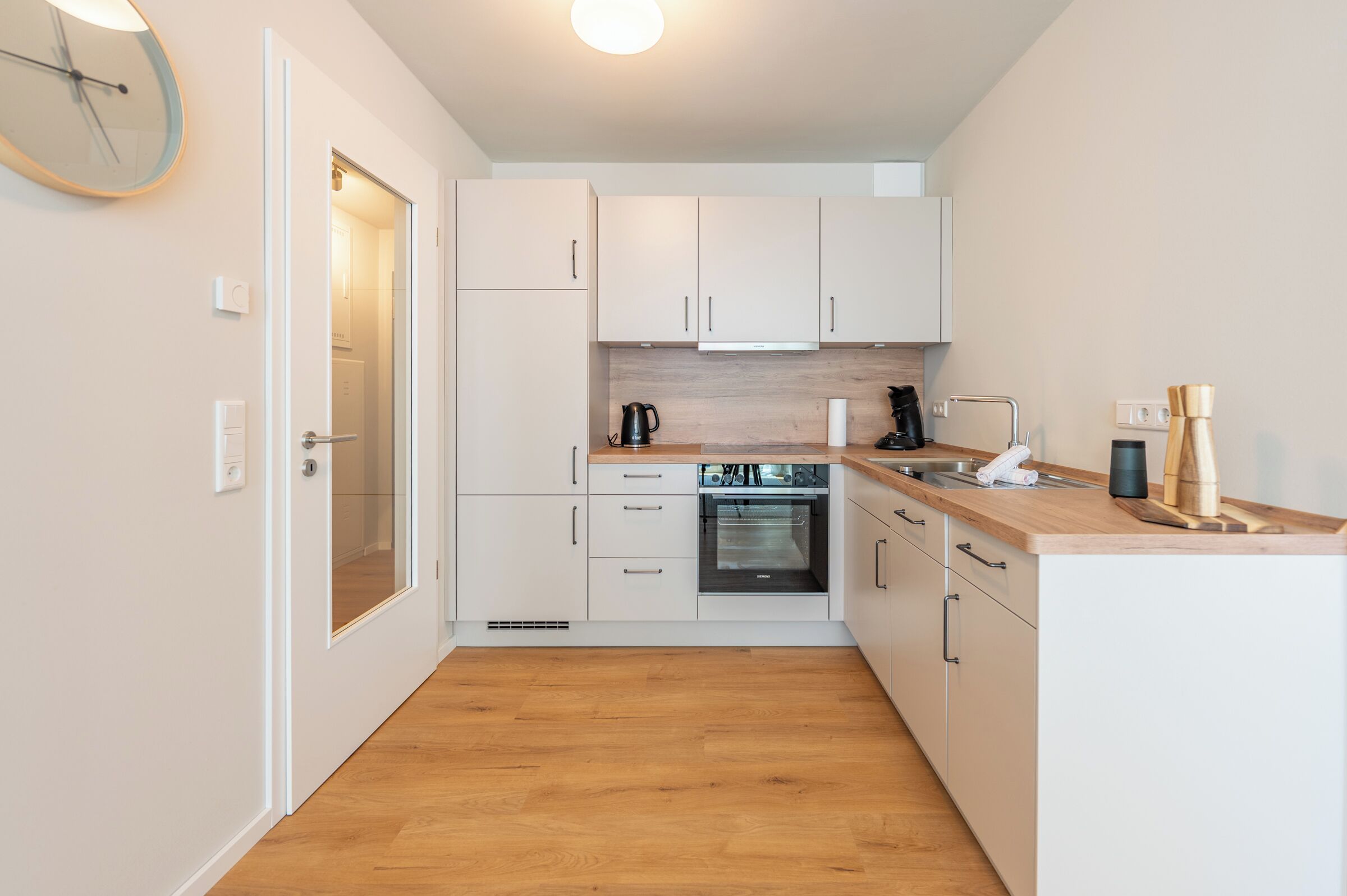 Une cuisine de taille réduite avec des meubles blancs, un four encastré et un plan de travail en bois.