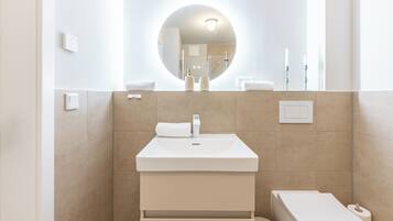 Une salle de bain moderne avec un miroir rond, un lavabo et des toilettes.