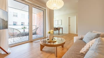 A modern living room with a glass coffee table, a sofa, and a dining area with chairs.