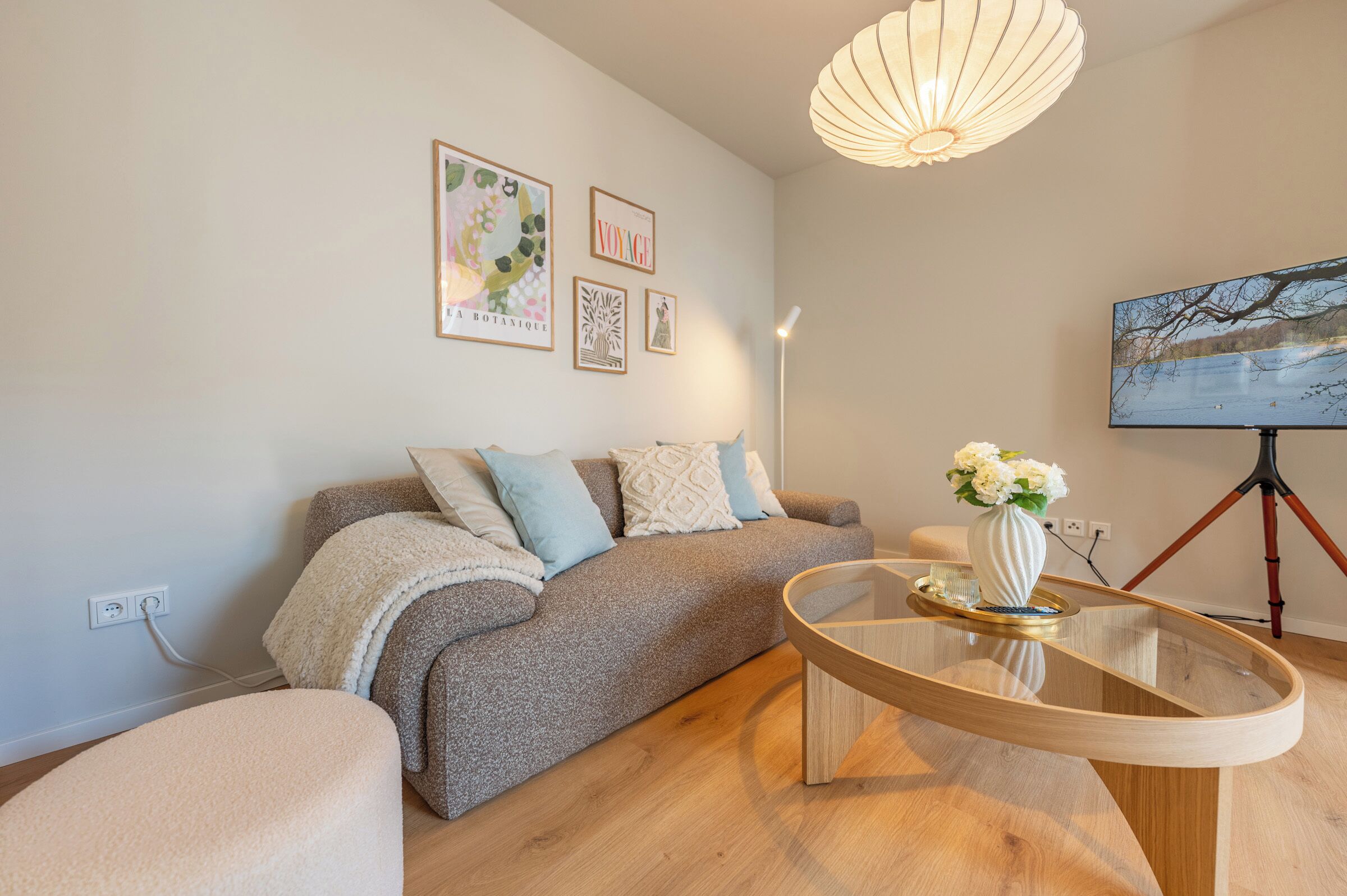 Ein modernes Wohnzimmer mit einer Couch, einem Glastisch und einem Gemälde an der Wand.