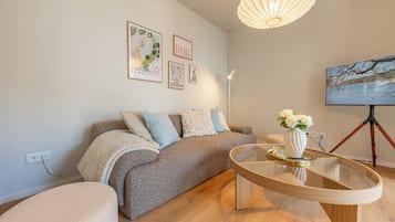 En moderne stue med en sofa, et glasbord og et maleri på væggen.