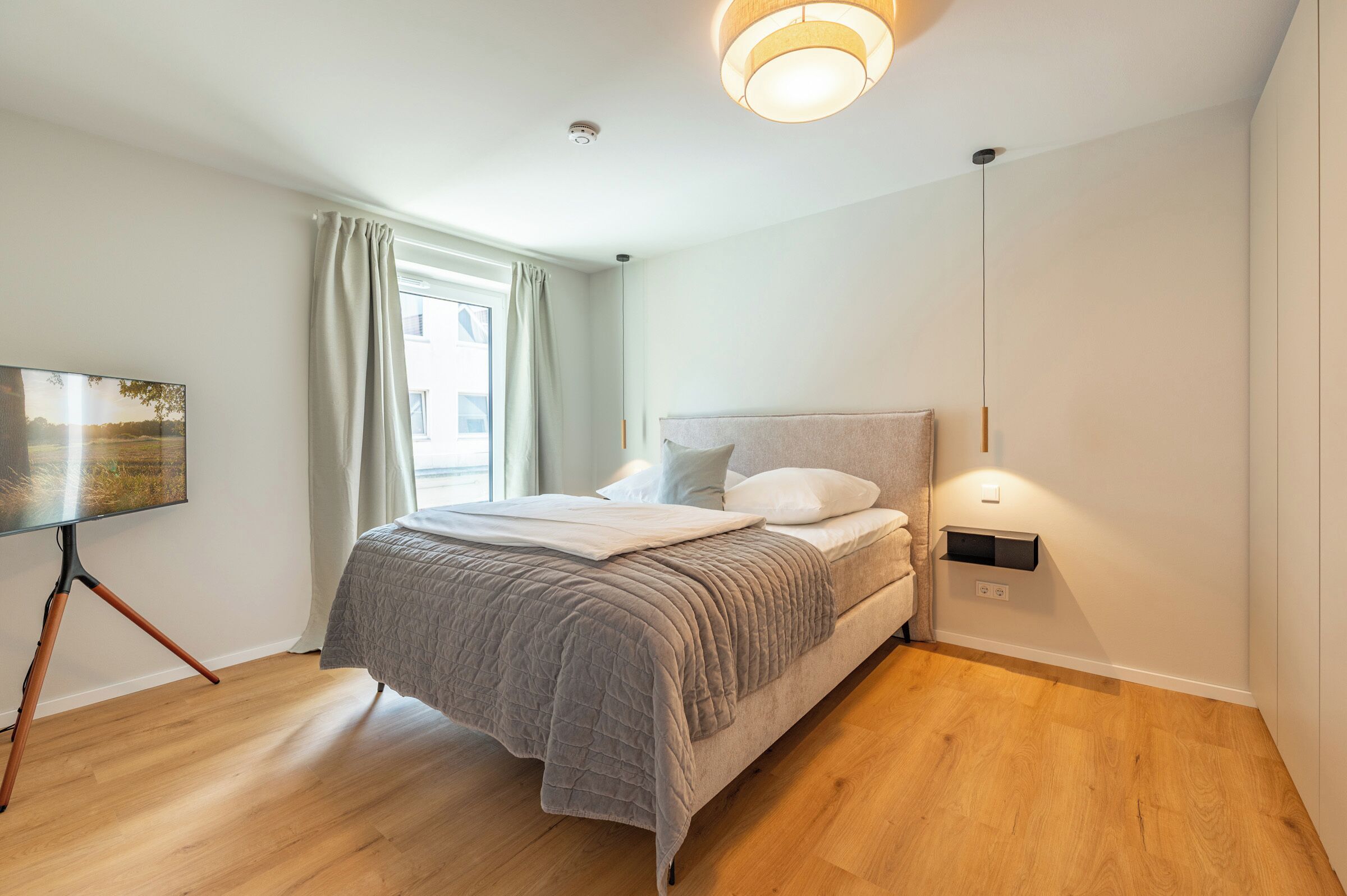 Une chambre à coucher moderne avec un lit, une table de chevet, une lampe et un tableau au mur.