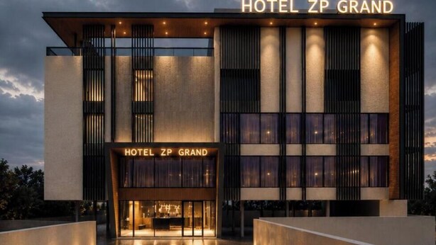 Um edifício moderno de hotel com entrada destacada e sinalização iluminada.