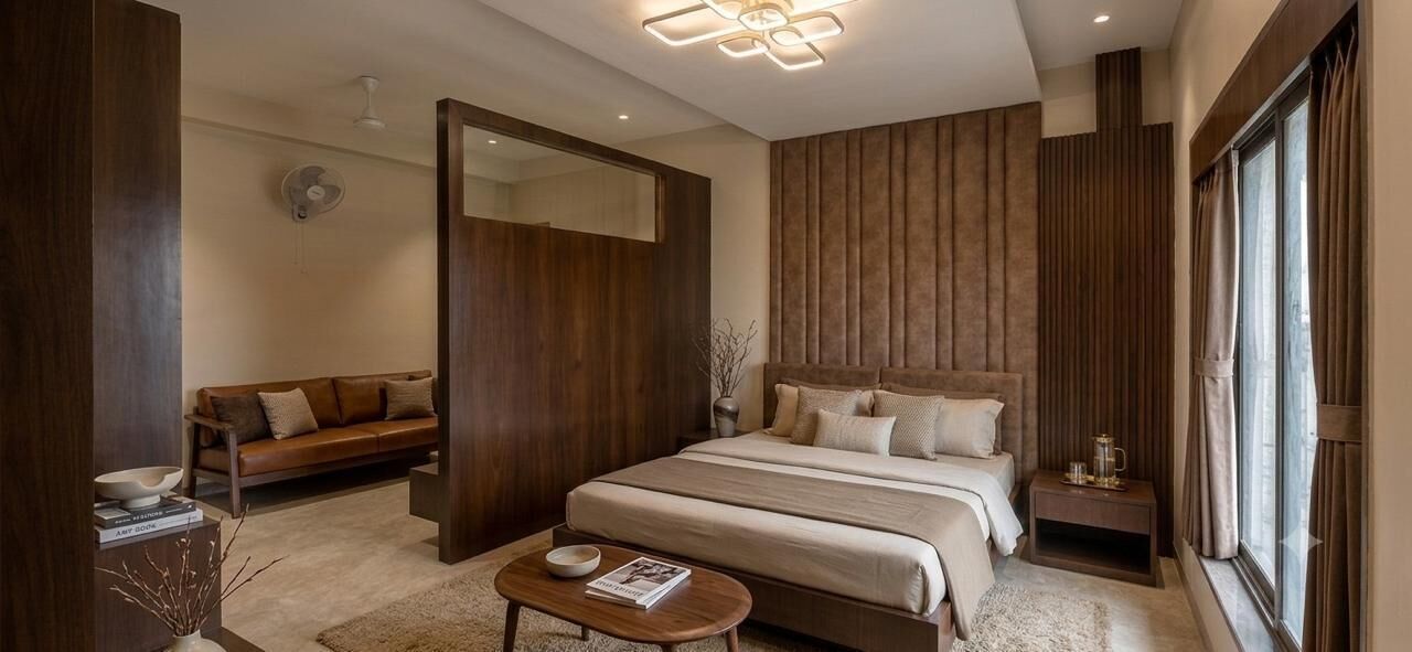Een moderne slaapkamer met een groot bed, een sofa, een nachtkastje en een spiegel.