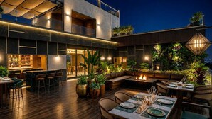 Uma área moderna para refeições ao ar livre, com bar, assentos e plantas.