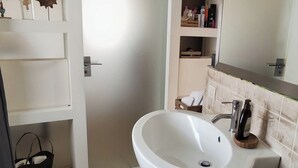 Un bagno con un lavandino bianco capiente, uno specchio e una panca in legno.