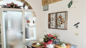 Un'area pranzo con un tavolo apparecchiato per due, un elemento decorativo a parete e una porta con pannelli vetro smerigliato.