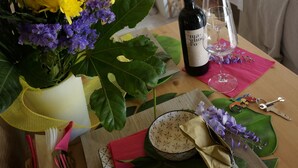 Un tavolo con una bottiglia di vino, un bicchiere, una ciotola e un bouquet di fiori.