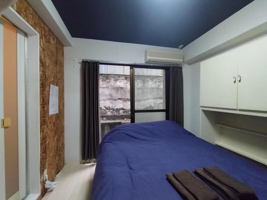 Ein Schlafzimmer mit einem Bett, einem Kleiderschrank und einem Fenster mit Vorhängen.