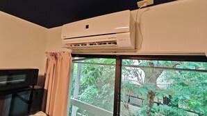 Una habitación con ventana, aire acondicionado, microondas y cortina.