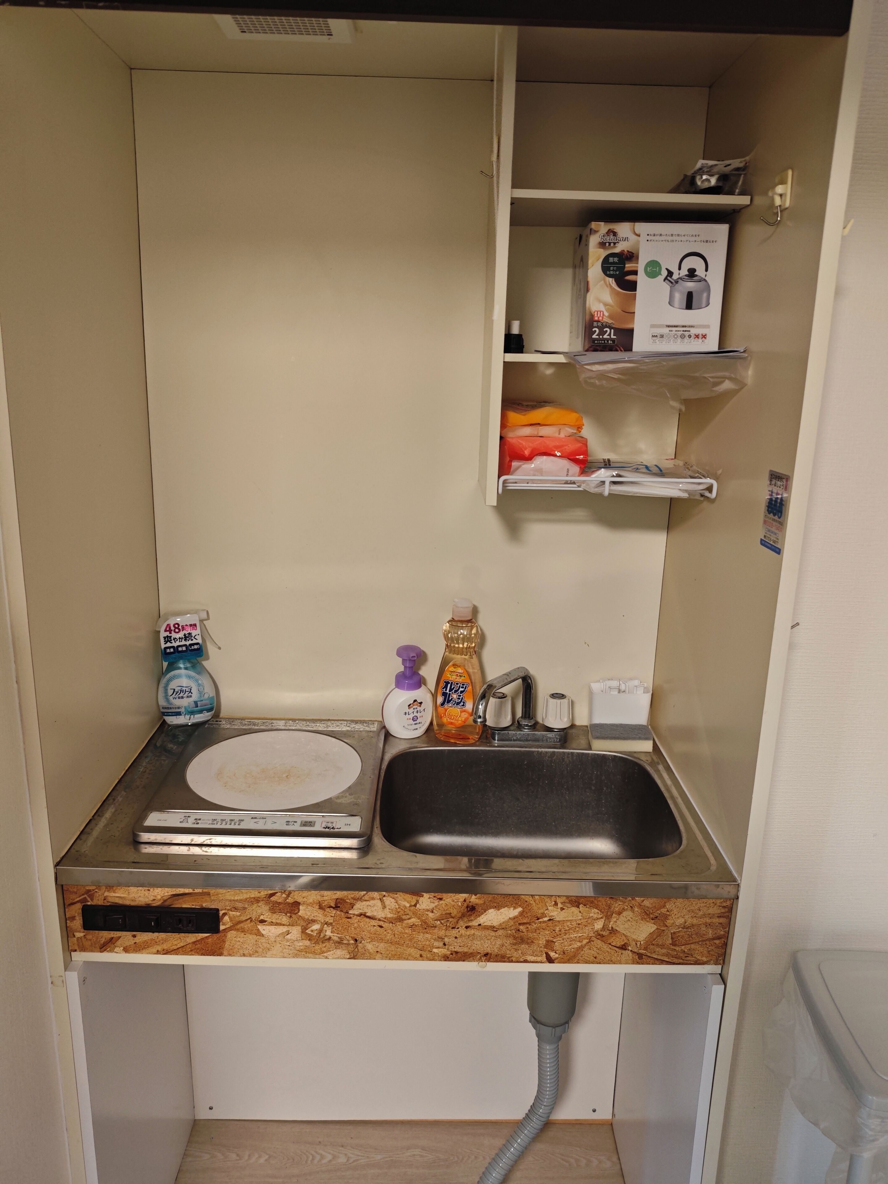 A compact kitchenette with a sink, a dish rack, a soap dispenser, and a bottle of dish soap.