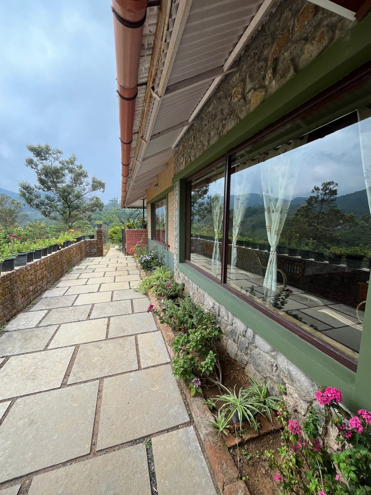 A stone pathway leading to a building with large windows overlooking a mountainous landscape.
