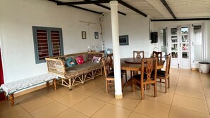 Une pièce spacieuse avec un plafond haut, une table à manger avec des chaises, un canapé avec des coussins et un banc.