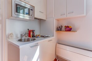 A compact kitchenette with a stainless steel sink, a microwave, and a small countertop with a coffee machine and utensils. - PIAZZA GRIMALDI AP4519 by Riviera Holiday Homes (Nice)