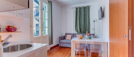 A compact kitchen with a sink, a dining area with a table and chairs, and a view of a building through a window.