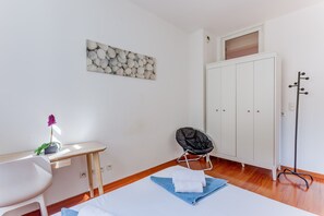 Ein Zimmer mit Schreibtisch, Stuhl, Kleiderhaken und Kleiderschrank.