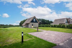 A rural property with a paved driveway leading to a house with a stone facade and a thatched roof. - Pet-Free Country House with Sauna (De Koog)