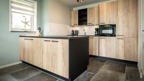 Une cuisine moderne avec des meubles en bois, un îlot central et une fenêtre équipée de stores.