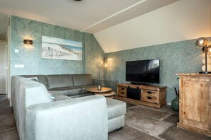 Ein Wohnzimmer mit einer Couch, einem Fernseher und einem Holzkabinett.