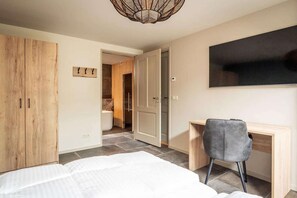 A bedroom with a bed, a desk, a chair, a wardrobe, and a television on the wall. - Pet-Free Country House with Sauna (De Koog)