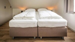 Une chambre avec deux lits, un plancher en bois et des lampes de chevet.