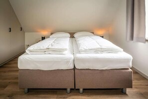 Ein Schlafzimmer mit zwei Betten, Holzboden und Nachttischlampen.