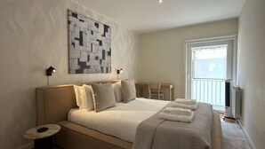 Ein Schlafzimmer mit einem Bett, Nachttischen, einem Schreibtisch und einem Fenster.